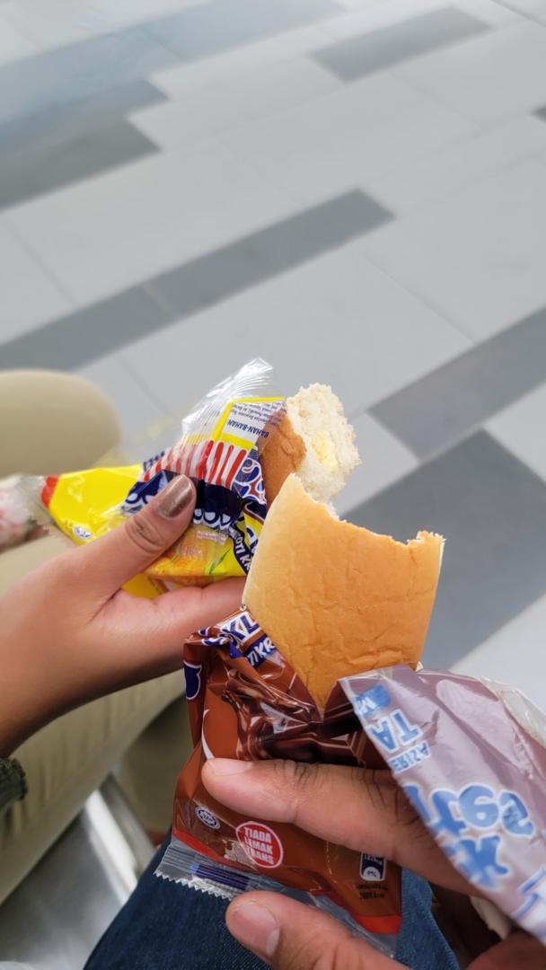 Both of your hands holding bread while waiting for the MRT