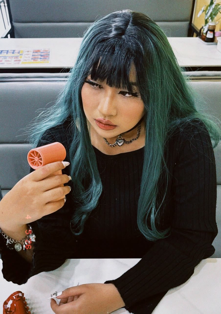 Sera wearing a teal wig and black outfit
