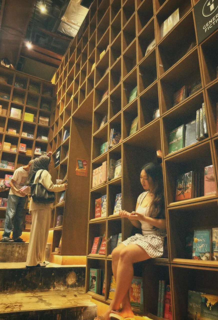 Sera sitting between tall bookstore shelves